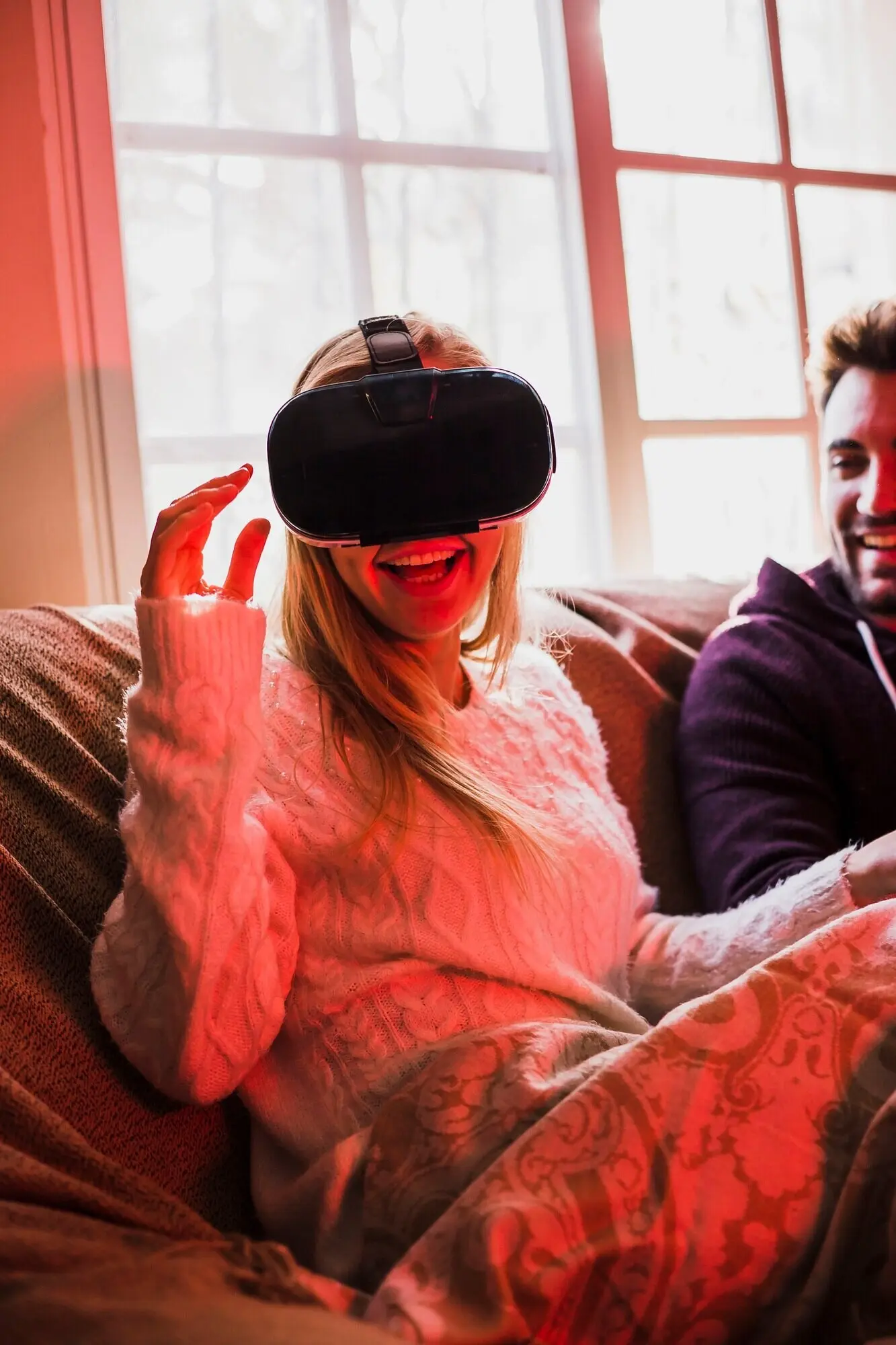 Весёлая женщина в VR-гарнитуре рядом с бойфрендом.